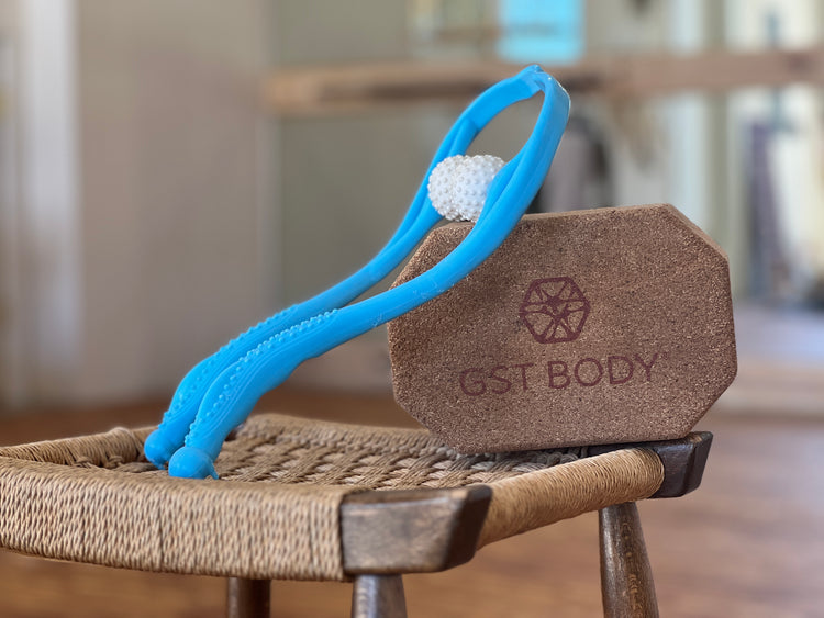 The GST Body Nexus Compression Tool, a blue dual-ball massager, is displayed resting on a cork block with the GST Body logo.